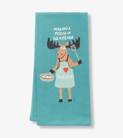 Turquoise tea towel featuring a cartoon moose in an apron holding a frying pan and spatula with the text "Making a Moose in…