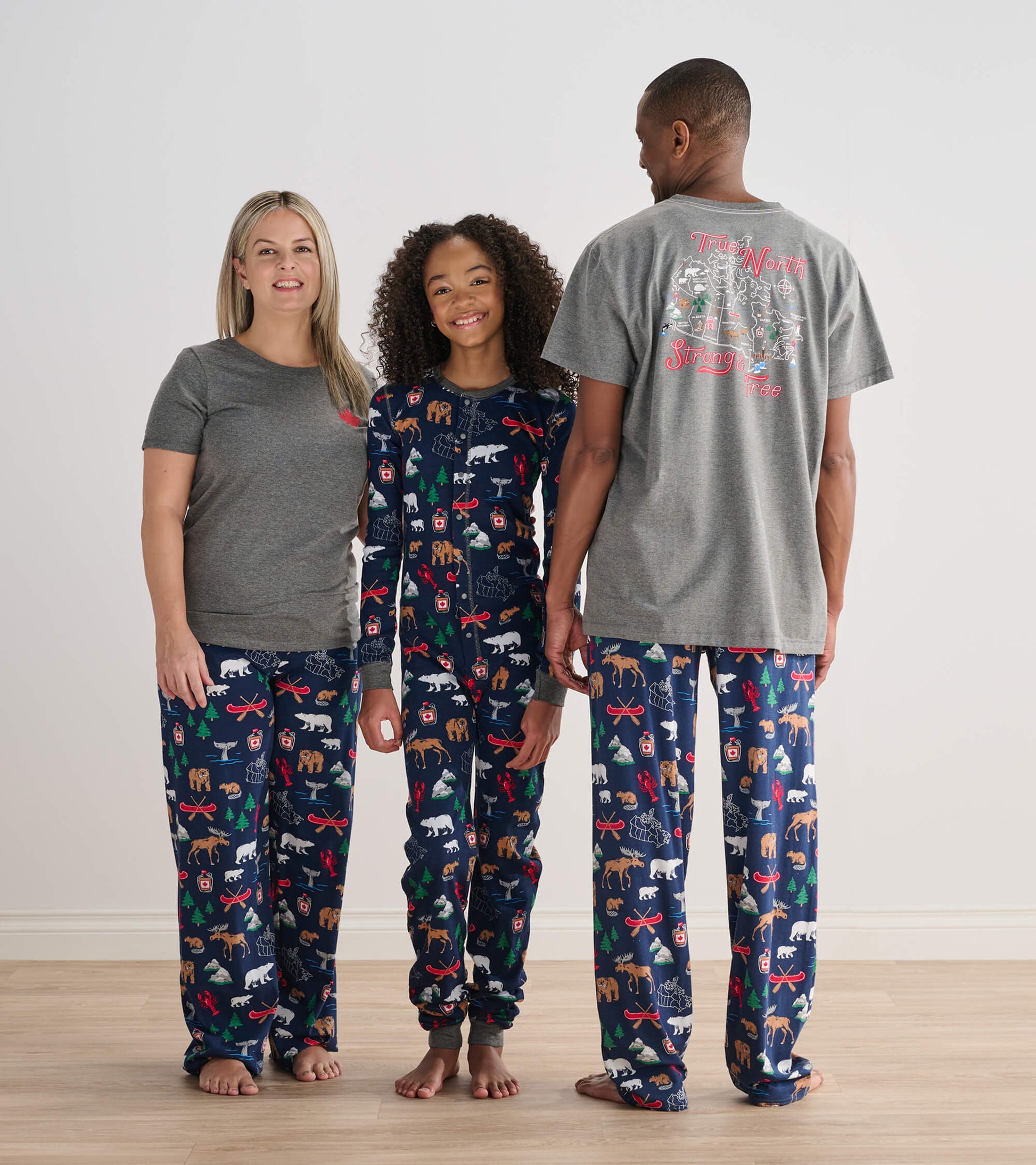 Child wearing navy True North printed onesie with adults in matching pajama bottoms and gray tops