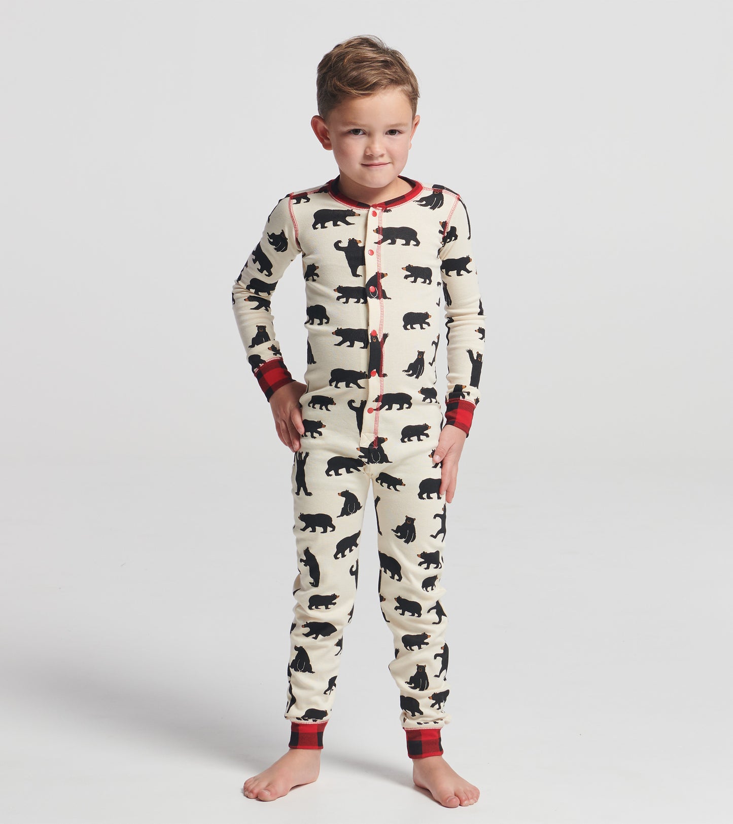 Cream-colored kids' onesie featuring black bear patterns and red plaid accents, designed for comfort and play.