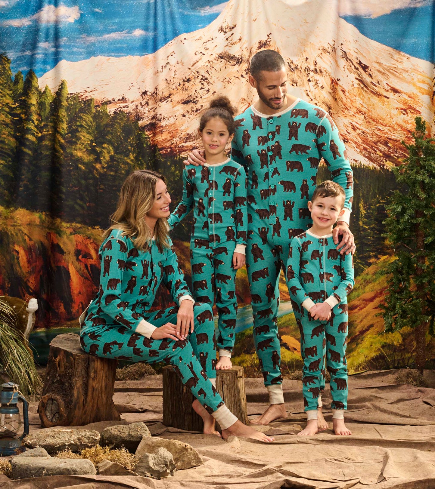 Turquoise onesie featuring brown bear patterns, worn by a family in a forest setting.