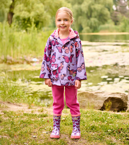 Girls purple butterfly-print shiny rain boots on a child standing outdoors, front view