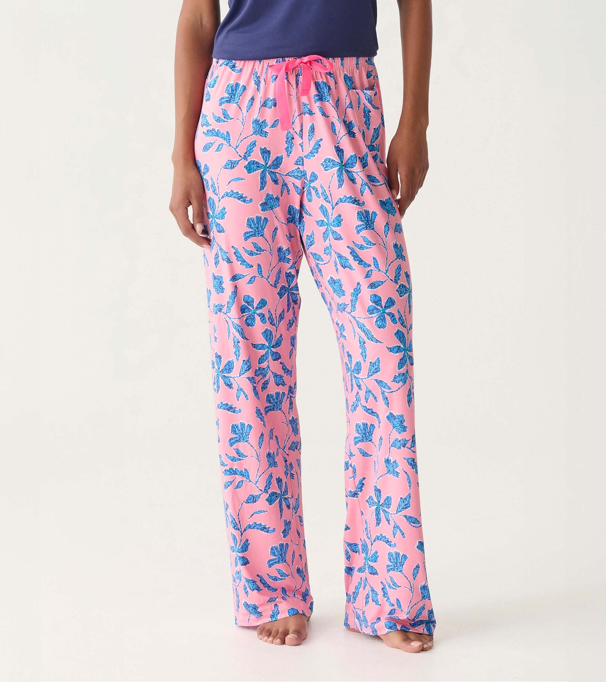 Pink pajama pants with blue floral print, drawstring waist, and straight legs on a model