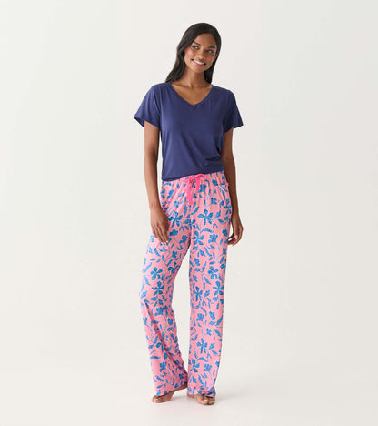 Pink floral pajama pants with blue batik flowers and a drawstring waist, shown on a model.