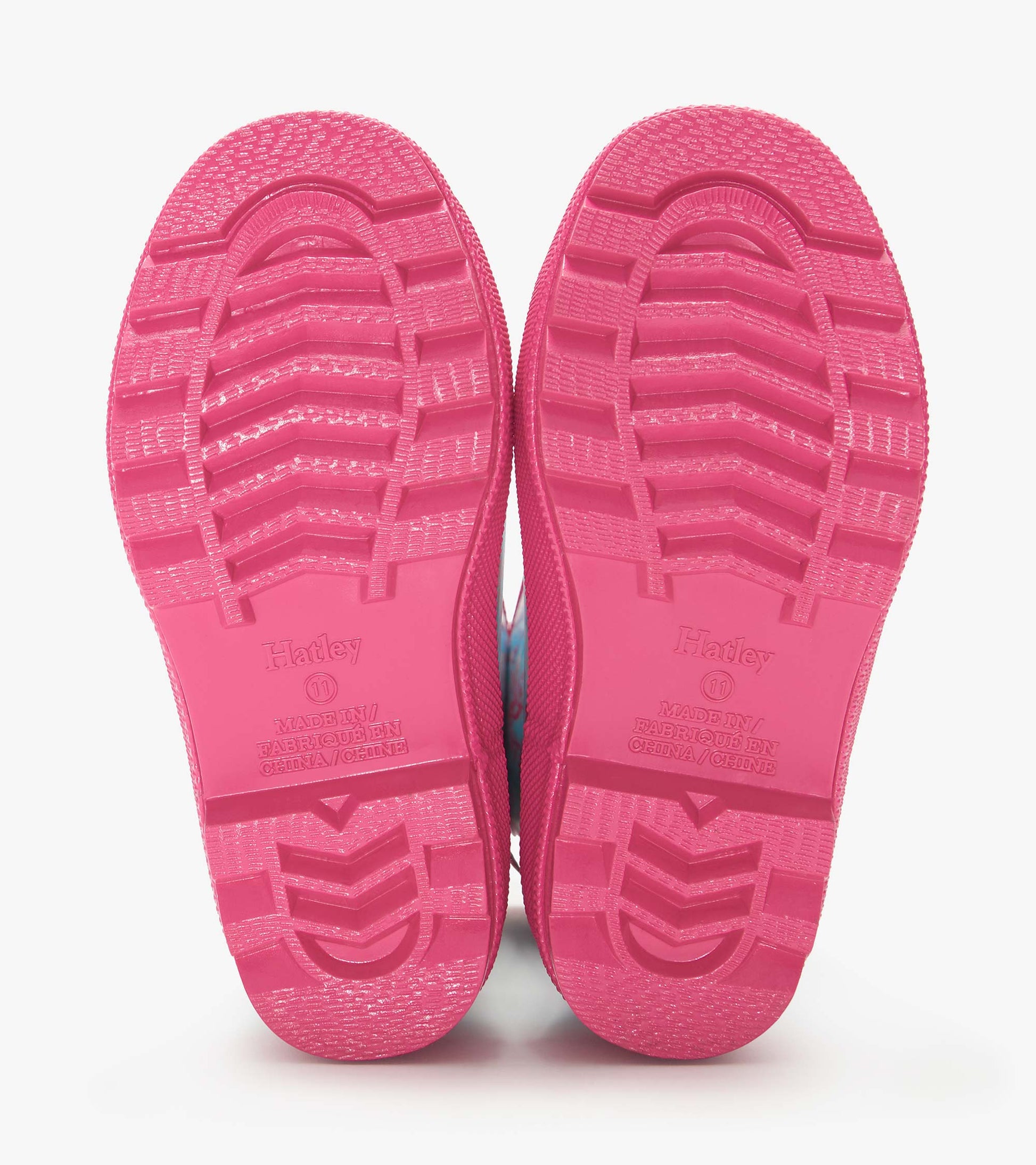 Pink rubber rain boots soles with textured tread, shown from the bottom view