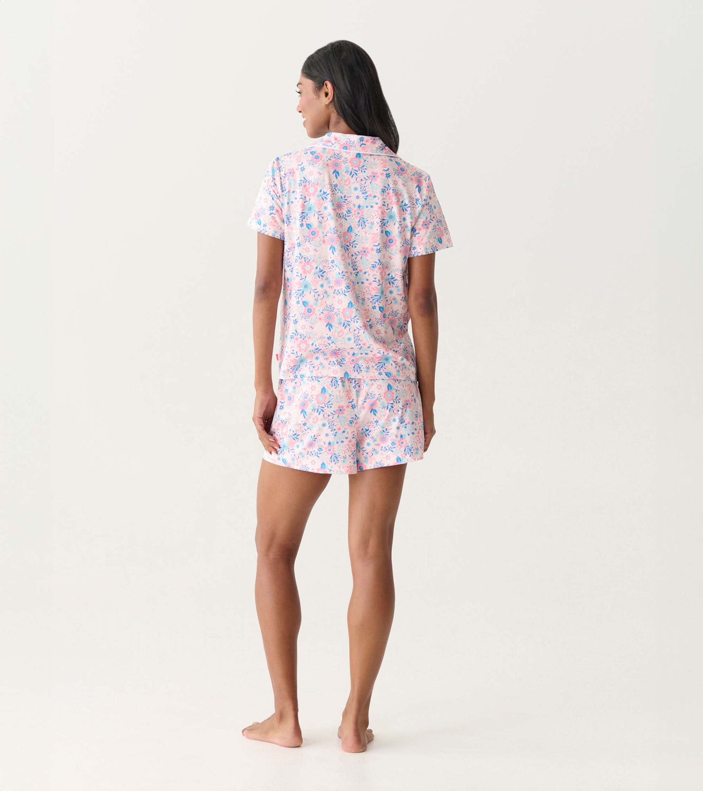 Back view of a pink and blue floral short-sleeve pajama set with button-down top and shorts