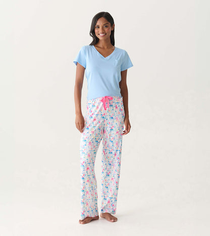 Woman wearing white pajama pants with colorful sailboat print and a light blue V-neck top, front view