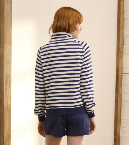 Mock neck pullover in navy and white stripes, featuring long sleeves and a relaxed fit, worn with shorts.