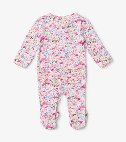 Baby footed sleeper featuring a colorful watercolor floral pattern with ruffle detailing at the back.