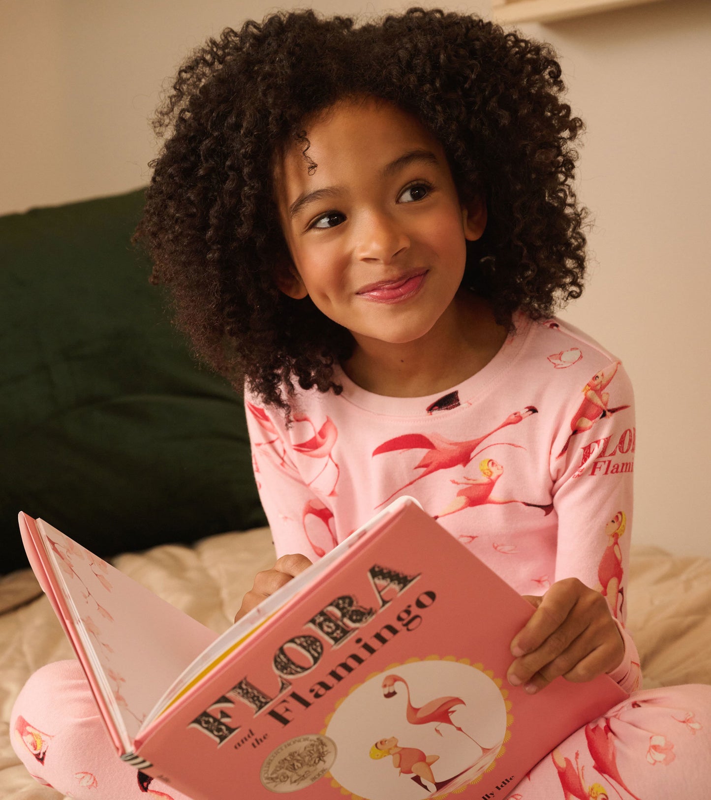 Pink pajama set with flamingo patterns, paired with a children's book featuring the same theme.
