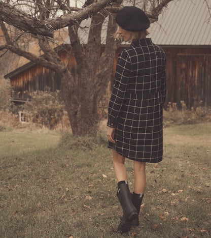 Black windowpane shirt dress with long sleeves, cinched waist, and a relaxed fit, worn with black rain boots.