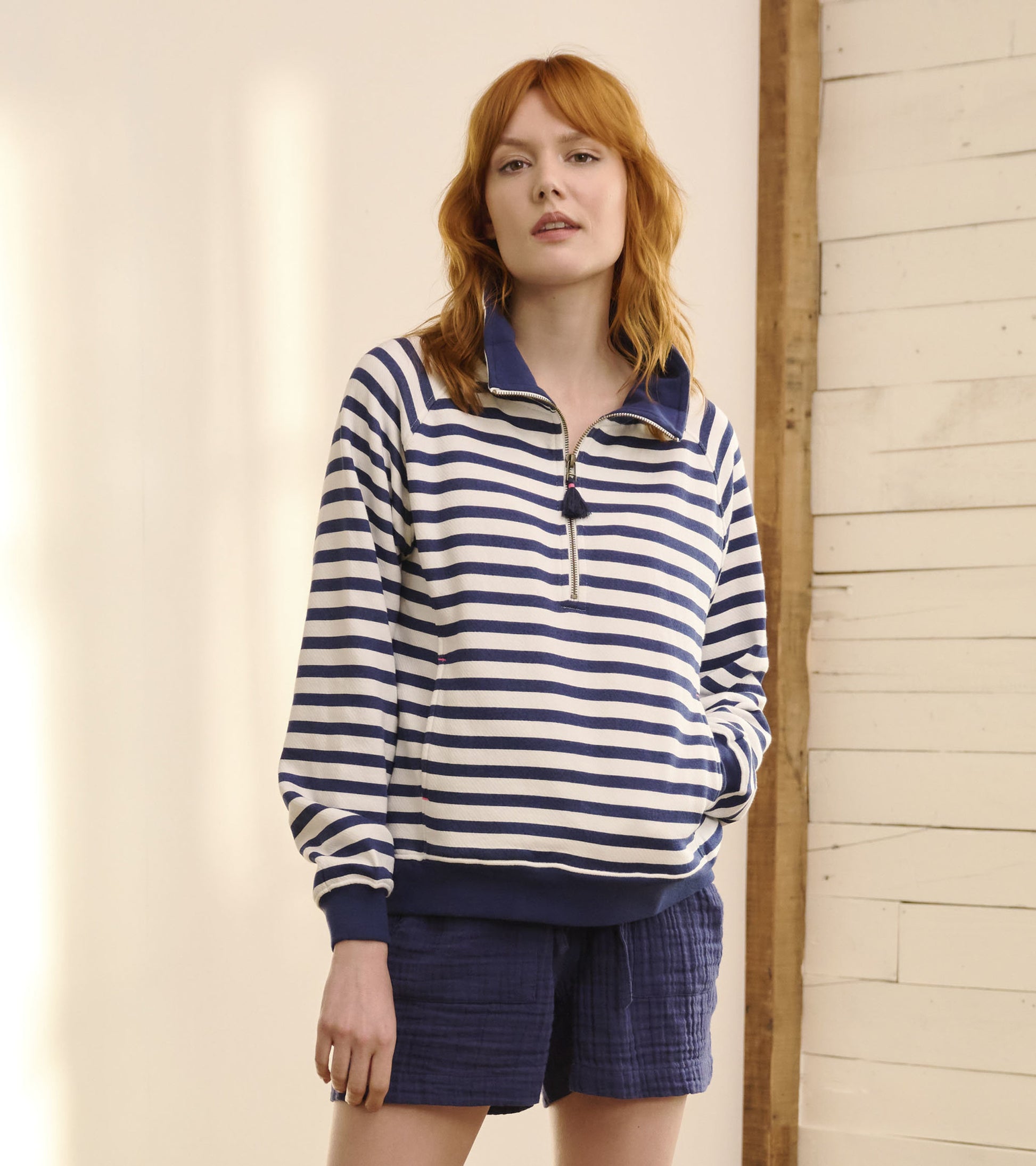 Mock neck pullover in navy and cream stripes, featuring a half-zip front and relaxed fit, paired with navy shorts.