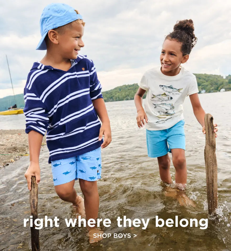 Promotes boys' clothing shopping. Showing two kids wading in shallow lake water wearing boys' summer outfits.